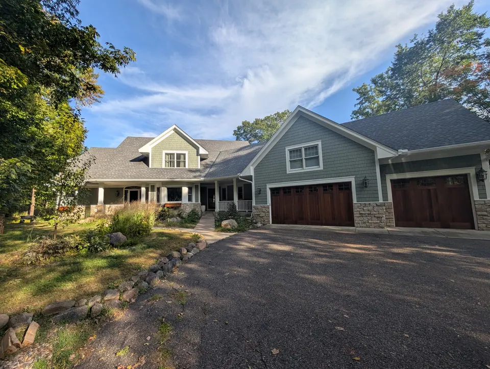 A home in Independence repainted sage green with white trim and stained wood garage doors